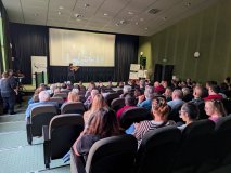 W sali kinowej odbywa się występ muzyczny. Na scenie stoi osoba grająca na skrzypcach, a za nią na d