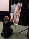 Anna Goc podpisuje plakat zapowiadający spotkanie autorskie poświęcone książce „Głusza”. 