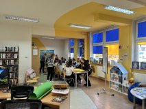 Widok na jasne, nowocześnie urządzone wnętrze biblioteki z żółtym sufitem, w którym dzieci pracują w