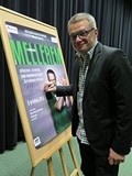 Marcin Meller podpisuje plakat promujący spotkanie w Koszalińskiej Bibliotece Publicznej