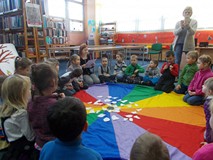 Bibliotekarka czyta książkę o zimie dzieciom, które siedzą na chuście
