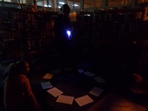 Bibliotekarka czyta dzieciom w ciemności, oświetlając tekst latarką