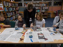 Bibliotekarka pomaga dzieciom w wykonywaniu pracy plastycznej