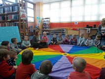 Bibliotekarka czyta dzieciom książkę na chuście animacyjnej