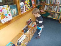 Chłopiec wybiera książkę z drewnianej skrzynki