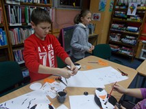 Dwoje dzieci siedzą przy stole i malują prace