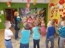 Bibliotekarka stoi przed dziećmi, które naśladują jej ruchy