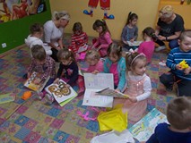 Dzieci siedzą na dywanie i oglądają książki