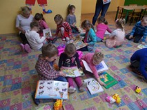 Dzieci z nauczycielkami siedzą i oglądają książki