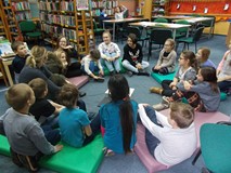 bibliotekarka i dzieci siedzą w kole i dyskutują