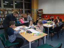 dzieci malują farbami, bibliotekarka rozmawia przy stoliku z dzieckiem