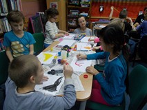 dzieci siedzą przy stole i malują farbami