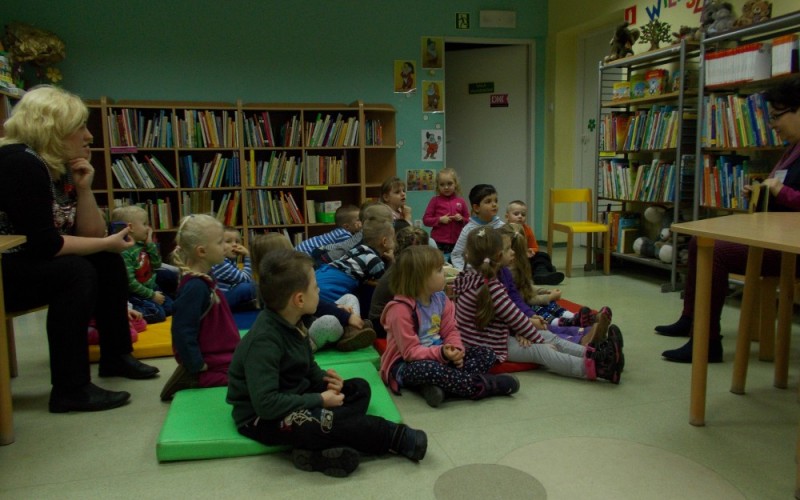 Przedszkolaki siedzące na kolorowych materacach w wypożyczalni dziecięcej filii nr 9. Pani...