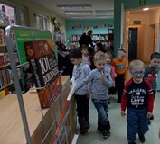 Grupa przedszkolaków z zaciekawieniem rozgląda się po dziecięcej wypożyczalni. Jedni gotowi są do za