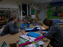 Zajęcia z maluchami. Dwoje dzieci siedzi przy stole, na którym znajdują się kolorowe kartki, bibuła,