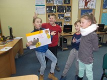 Dzieci stoją i pozują do zdjęcia, pokazując swoją pracę