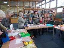 Panie robią na drutach i wycinają serca z filcu na stołach