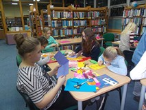 dzieci ozdabiają kartki walentynkowe przy stołach