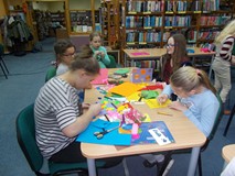 dzieci siedzą przy stołach i wykonują kartki walentynkowe