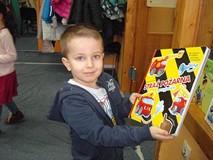 Chłopiec pozuje do zdjęcia z książką