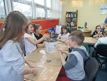 Dzieci siedzą przy stole i wykonują pracę z masy papierowej