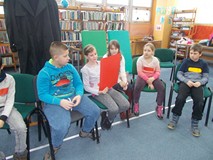 Dzieci siedzą na krzesłach w drużynie i prezentują swoją pracę