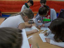 Dzieci stoją przy stole i malują rekwizyty