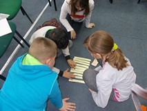 Troje dzieci siedzi i szereguje w kolejności cechy dobrego detektywa