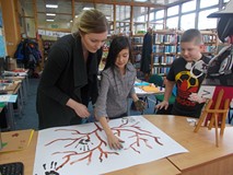 Bibliotekarka pomaga dziewczynce odcisnąć dłoń na brystolu