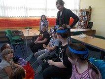 Bibliotekarka stoi za dziećmi mającymi ilustracje na głowie