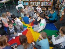 Dzieci siedzą na chuście animacyjnej i oglądają książki