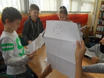 Dzieci stoją przy stole i pokazują gotową pracę