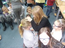 dzieci siedzą na dywanie, a dziewczyna maluje twarz dziewczynki