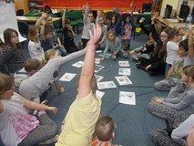 dzieci siedza na dywanie w kole z ilustracjami