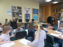 Dzieci siedzą przed bibliotekarką przebraną za detektywa