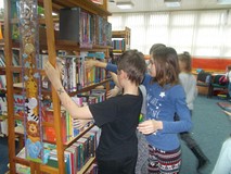 Dzieci stoją przed regałem i szukają ksiązki