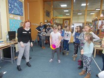 Dzieci stoją z bibliotekarką, a dziewczynka trzyma w ręku piłkę