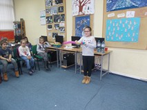 Dziewczynka stoi przed dziećmi i pompuje balona