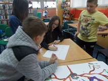 Dzieci siedzą i zapisują odpowiedzi na kartce