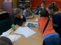 Dzieci siedzą razem w grupie i pracują nad odpowiedziami