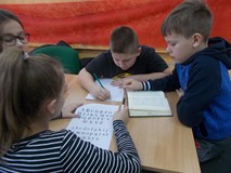 Dzieci siedzą w grupie i piszą odpowiedzi