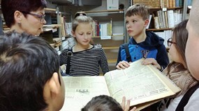 Dzieci stoją przed panią z magazynu i trzymają czasopismo