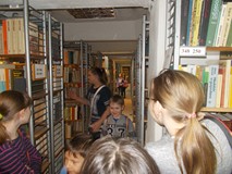 Dzieci szukają książek w regałach magazynu biblioteki