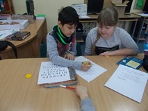 Dziewczynka i chłopiec siedzą przy stole i zapisują odpowiedzi