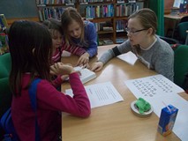 Dziewczynki siedzą przy stole i szukają informacji w książce