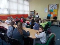 Bibliotekarka objaśnia dzieciom siedzącym przy stole zadanie do wykonania