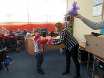 Bibliotekarka wręcza dziecku upominek na zakończenie zajęć feryjnych