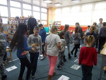 Dzieci przechadzają się między ilustracjami przedstawiającymi sylwetki znanych detektywów