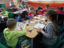 Dzieci przy stołach wykonują pracę plastyczną