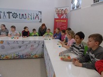 Dzieci siedzą przy stole z kubkami z kolorową wodą